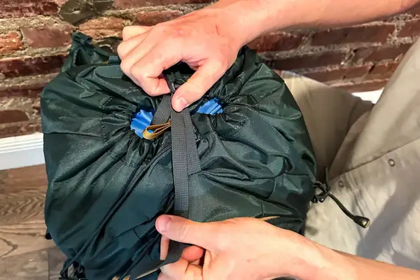 Hands securing the drawstring of a Gregory Katamai 55 - Hiking Backpack 