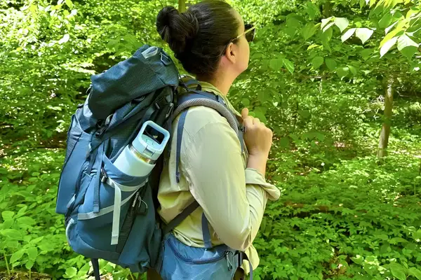 Person wearing a REI Co-op Traverse 60 Pack with hiking gear standing amidst nature
