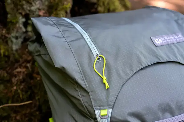 Close-up of a green Gossamer Gear Mariposa 60 Backpack with a zippered pocket and yellow cord