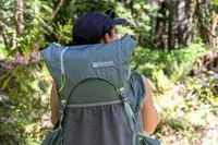 A person wearing a Gossamer Gear Mariposa 60 Backpack in a forested area