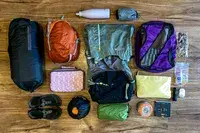 Arranged backpacking essentials including bags, food, and gear with the Gossamer Gear Mariposa 60 Backpack