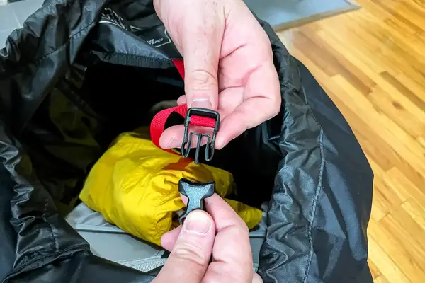 Hands holding and fastening a buckle on a strap in a Osprey Atmos AG 65 Men