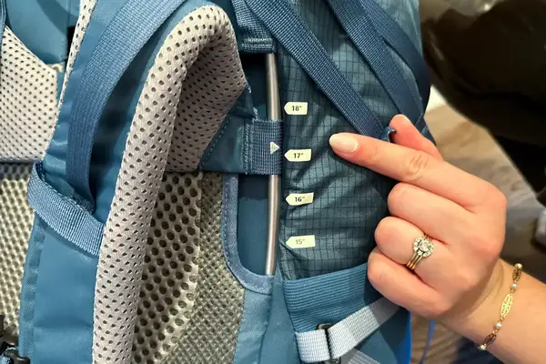 Person adjusting a REI Co-op Traverse 60 Pack strap with torso length markers