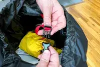 Hands holding and fastening a buckle on a strap in a Osprey Atmos AG 65 Men