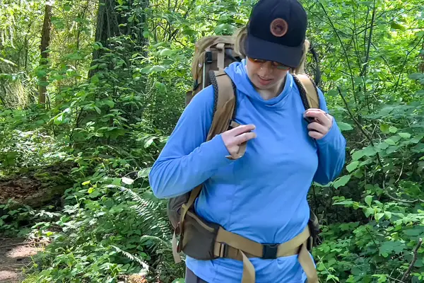 Person hiking in a forest, wearing a The North Face Trail Lite 50 Backpack and a hat