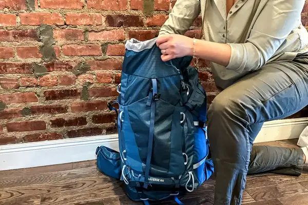 Person adjusting a large REI Co-op Traverse 60 Pack in front of a brick wall