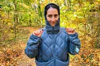 Person tugging on straps of Hikerkind Packable Down Puffer 0.1.