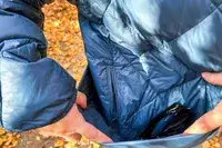 Person opening up side pockets of Hikerkind Packable Down Puffer 0.1.