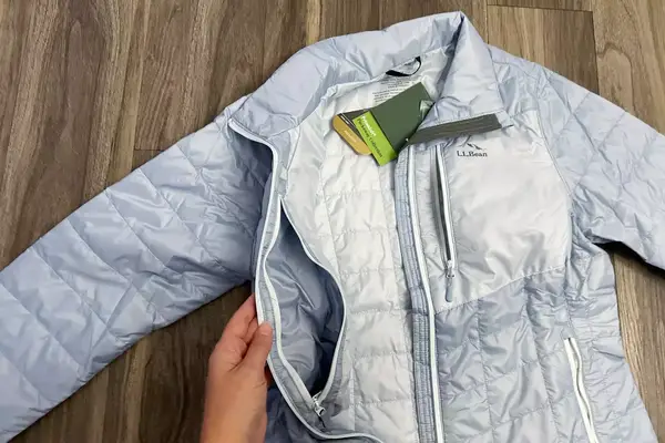 A hand holds the side interior pocket of the L.L.Bean Women’s PrimaLoft Packaway Jacket open