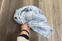 A hand holds a folded up L.L.Bean Women’s PrimaLoft Packaway Jacket