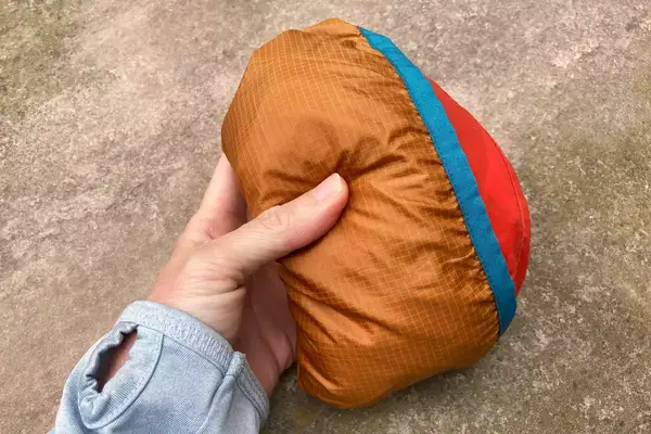 A hand holding a folded up Cotopaxi Women