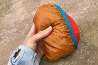 A hand holding a folded up Cotopaxi Women