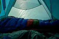 A person sleeps in the Marmot Sawtooth 15 Sleeping Bag inside a tent
