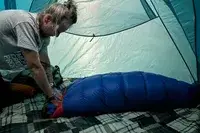 A person rolls up the Marmot Sawtooth 15 Sleeping Bag