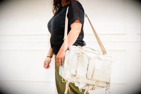 A person wears the Calpak Terra 26L Laptop Duffel Backpack by the strap