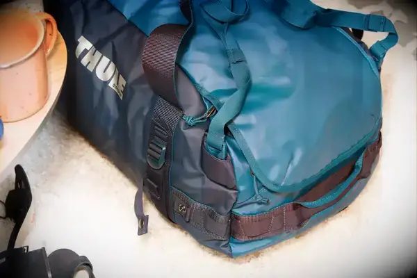 A person places the Calpak Terra 26L Laptop Duffel Backpack into an overhead compartment