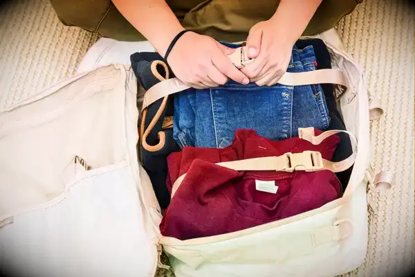A person secures clothing inside the Calpak Terra 26L Laptop Duffel Backpack