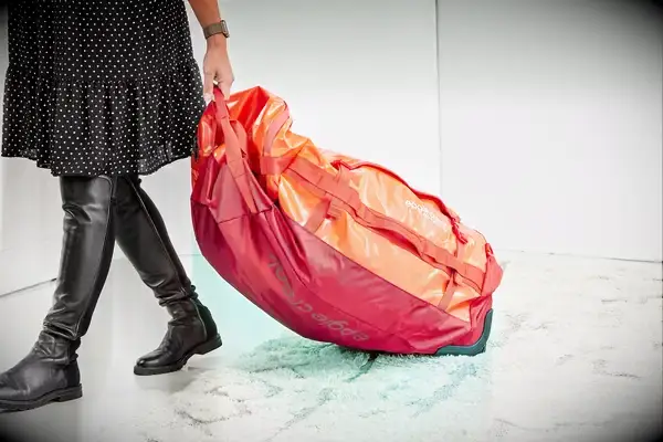 A person wears the Calpak Terra 26L Laptop Duffel Backpack by the strap