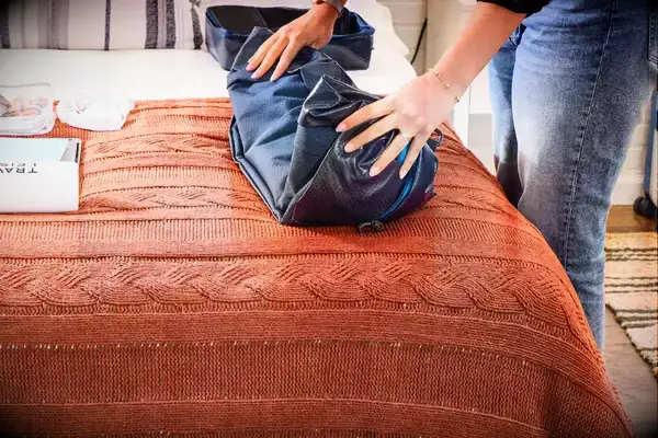 A person folds up the Gregory Alpaca Duffel 60L
