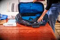A person places travel items into the Gregory Alpaca Duffel 60L