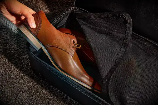 A hand adding a shoe into The Convertible Weekender