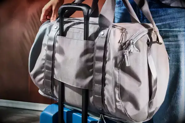 The Dagne Dover Lagos Convertible Duffle Bag on suitcase handles