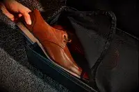 A hand adding a shoe into The Convertible Weekender