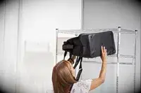 A person lifting the The Convertible Weekender onto a rack