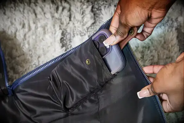 Hands putting a phone into the Mark & Graham Commuter 2-in-1 Garment Bag