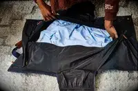 Hands zipping the Mark & Graham Commuter 2-in-1 Garment Bag with clothing inside