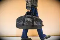 A person carries a Samsonite Ecodiver Small Duffel bag