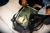 A person packing clothes into the Dagne Dover Lagos Convertible Duffle Bag