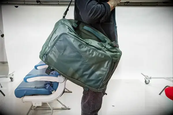 A person carries the Away The Outdoor Convertible Backpack 45L by the shoulder strap