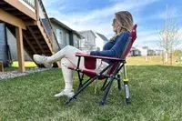 A person sits in the GCI Outdoor Kickback Rocker Chair