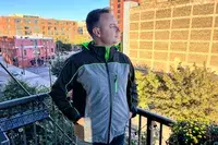 A person standing on a balcony while wearing the Conqueco Men