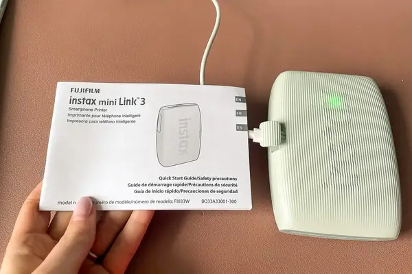 A Fujifilm Instax Mini Link 3 smartphone printer with accompanying user guide
