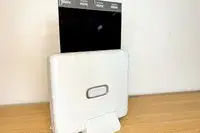 An Instax printer on a wooden surface with a film being printed out