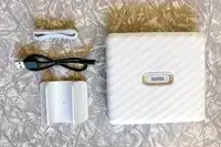 A compact photo printer with accessories laid out on a surface