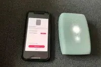 A smartphone displaying a printer connection interface next to a compact portable printer