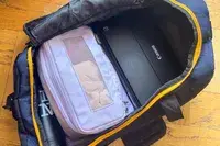 Open backpack displaying items like a Canon printer and a lightcolored pouch