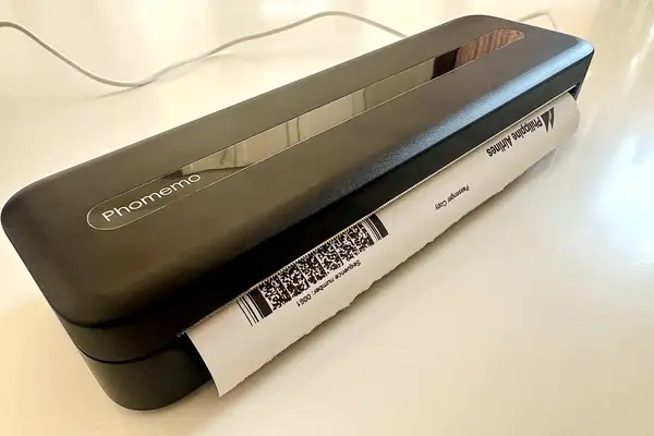 A compact device printing a document brand name Phomemo visible