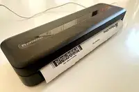 A compact device printing a document brand name Phomemo visible