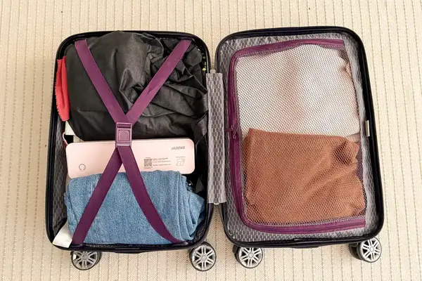 An open suitcase packed with clothing and JADENS Bluetooth Thermal Printer organized with straps and netting