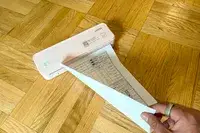A person using JADENS Bluetooth Thermal Printer to print a form on a wooden floor