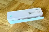 JADENS Bluetooth Thermal Printer with a partially printed document on a wooden floor surface