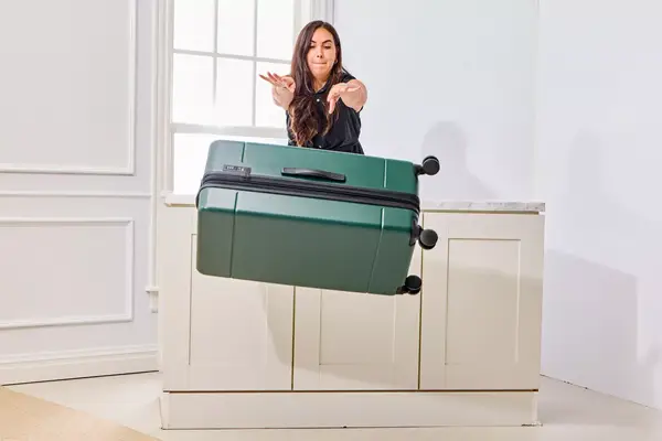 A person pushes the Calpak Hue Trunk Luggage off onto the floor