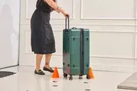 A person rolling the Calpak Hue Trunk Luggage through an obstacle course