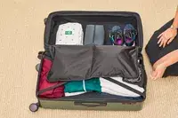 A person packs the Calpak Hue Trunk Luggage