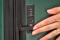 A person touches the lock on the Calpak Hue Trunk Luggage