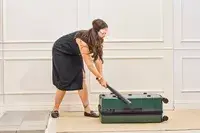 A person hits the Calpak Hue Trunk Luggage with a bat